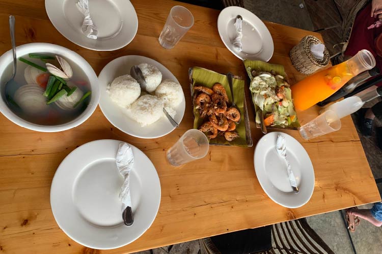 テーブルの上に、４種類のフィリピン料理とフルーツの入ったオレンジジュースがピッチチャーに入れられている