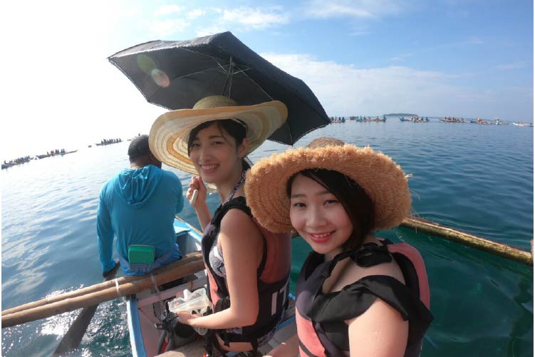 小舟に乗り海へ向かうツアー参加者女性2人