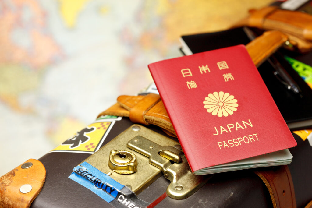 世界地図の上にキャリーケースとパスポートが写っている写真
