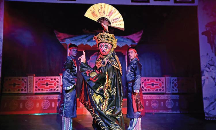 中国の伝統芸能　変面
皇帝の衣装を身に纏った変面の男性を補助役の2人の男性が見守っている様子