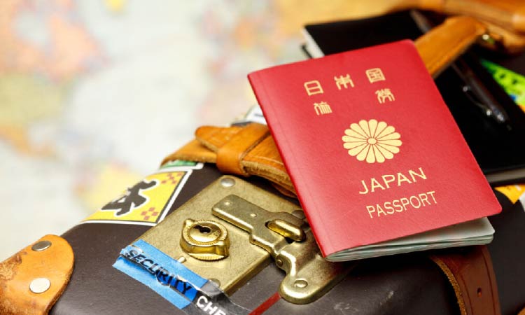 世界地図の上にキャリーケースとパスポートが写っている写真
