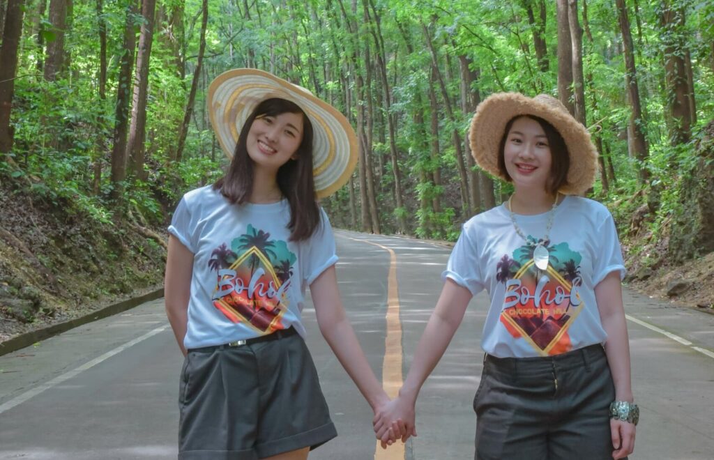 マンメイドフォレストを背景に写真を撮影する麦わら帽子の女性2人